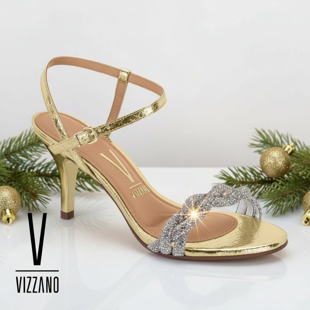 A gold-colored strappy sandal with a heel and rhinestone embellishments.