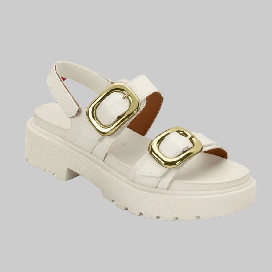 A white sandalia featuring a chunky sole and two large gold buckles on the strap.