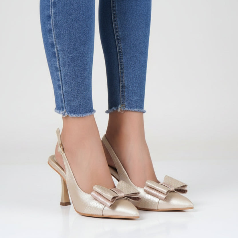 Gold high-heeled shoes with bows worn by a person in front.