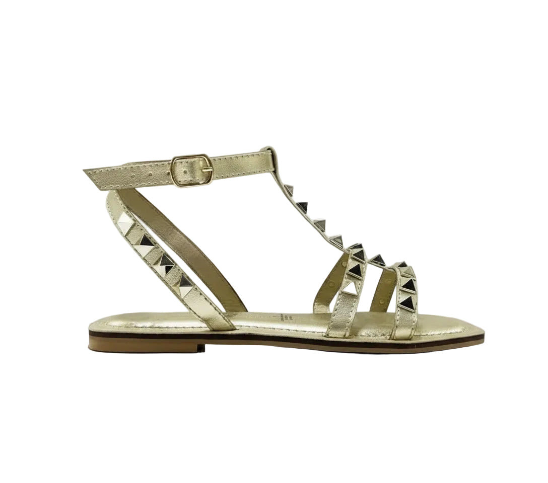 A gold flat sandal with ankle strap and metallic embellishments on the straps, featuring a man made upper, rubber outsole, and man made lining.