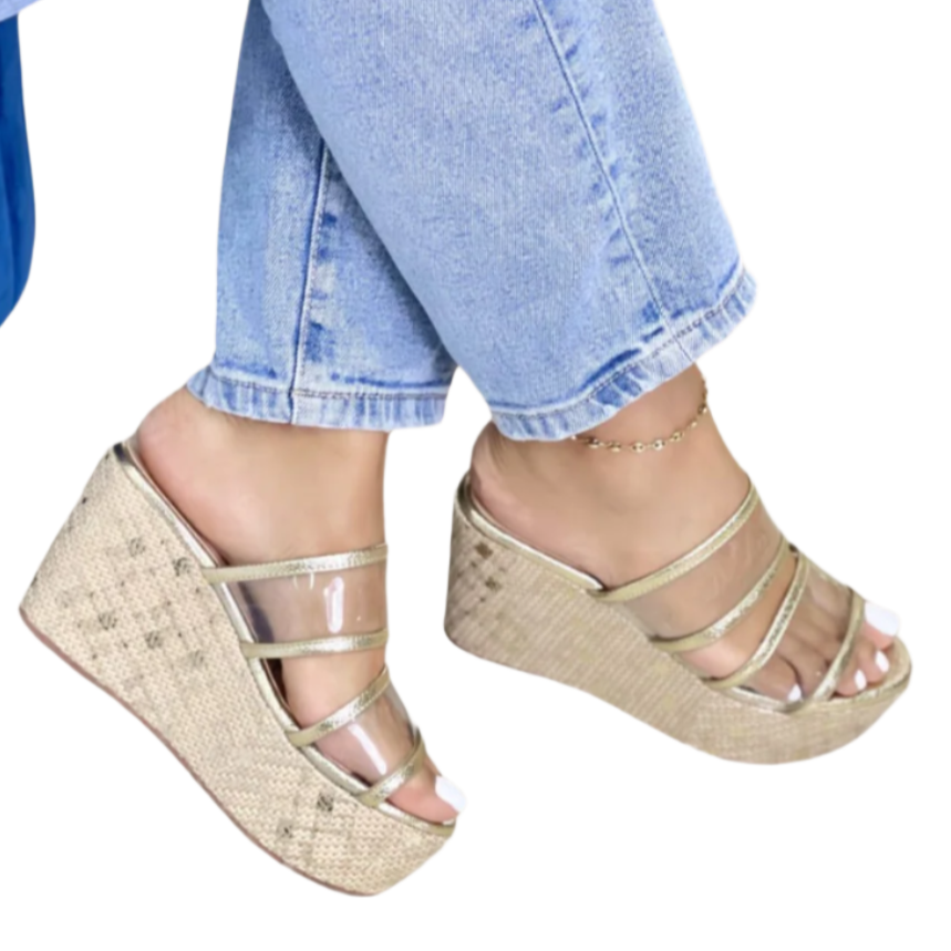 A pair of clear platform sandals with gold details.
