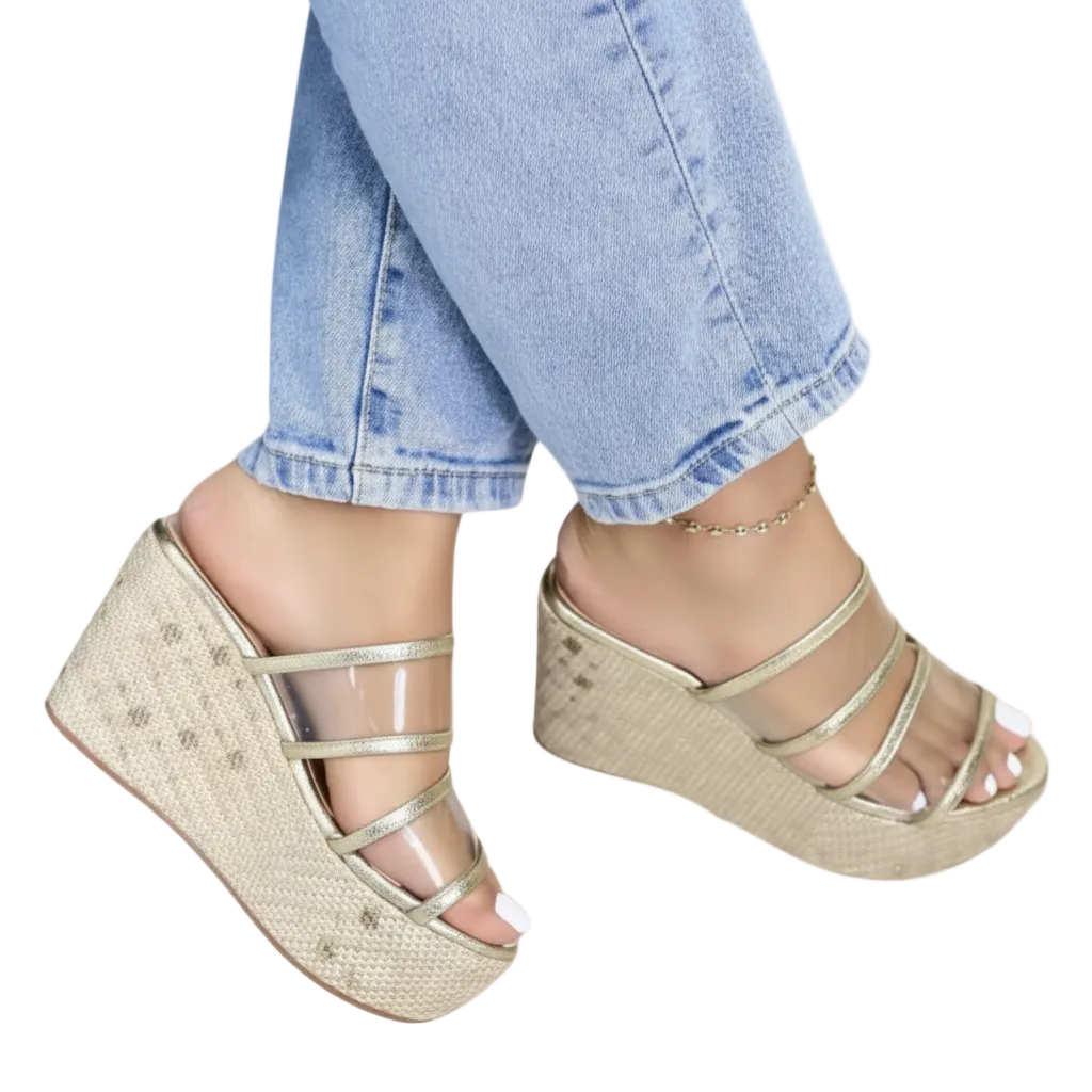 A pair of clear platform sandals with gold details.