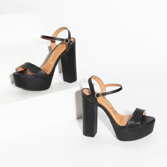 A pair of black platform sandals with thick heels and ankle straps.