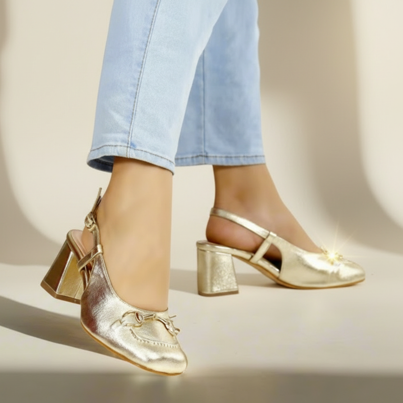 A pair of gold-colored Mary Jane style heels with square toes.