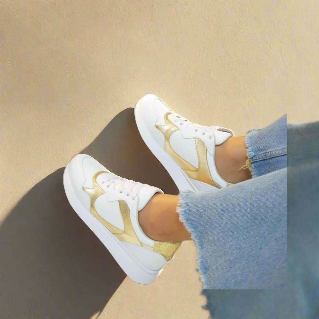 A pair of white sneakers with gold accents.