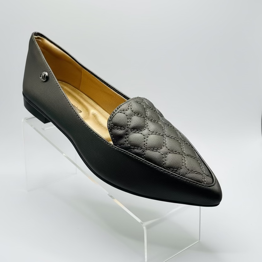 A black, quilted leather loafer with a pointed toe and a metallic embellishment.