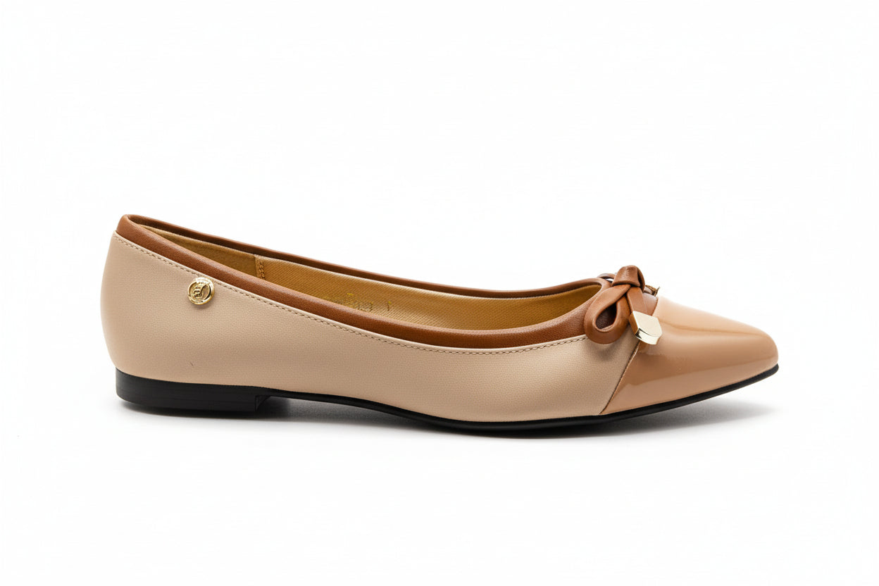 A beige-colored, pointed-toe ballet flat with a lace-up closure and gold-tone hardware.