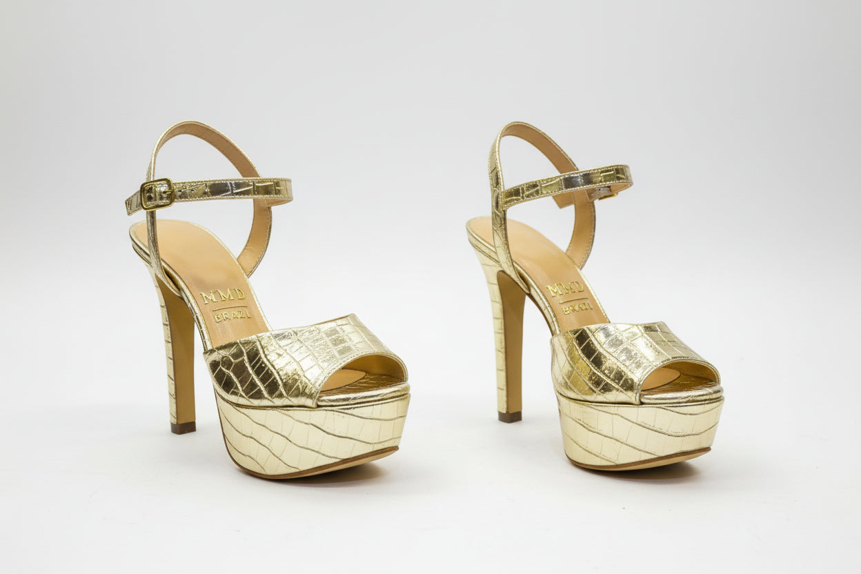 Gold high-heeled shoes with a Jayli Boutique sign in the background