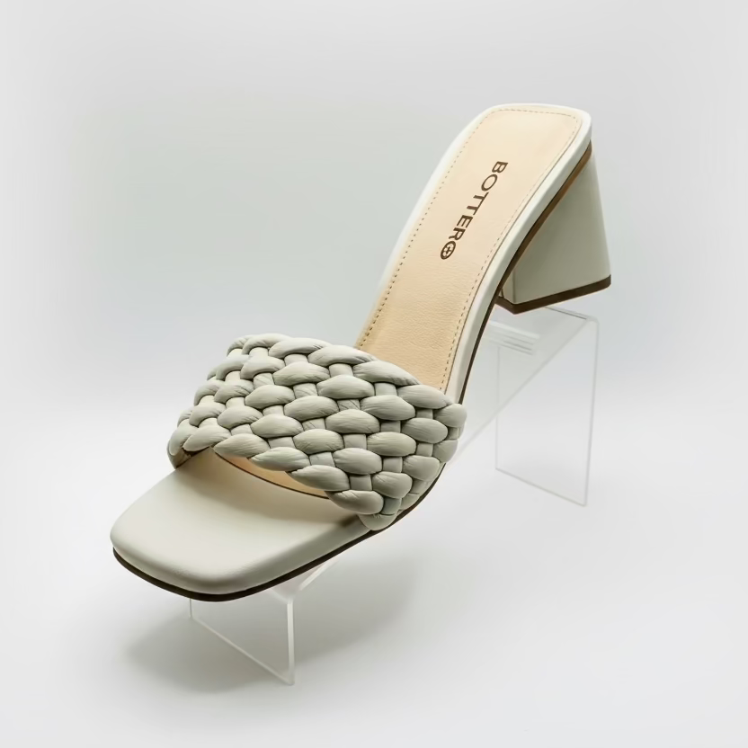 White sandal with braided detail on a white.