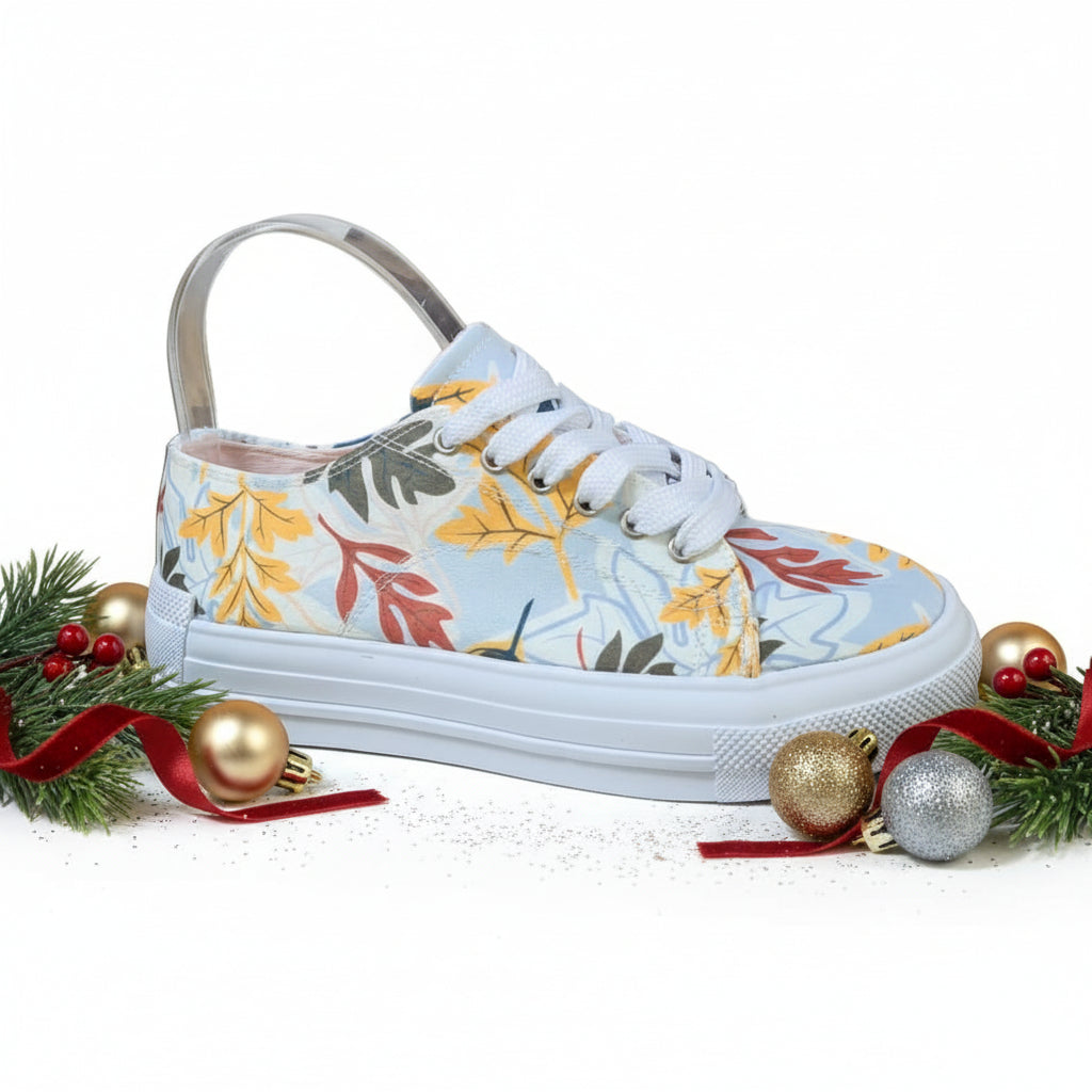 A pair of white sneakers with a floral pattern featuring yellow and green leaves.
