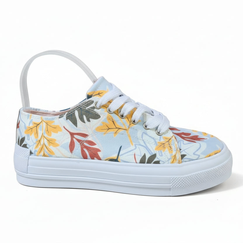 A pair of white sneakers with a floral pattern featuring yellow and green leaves.