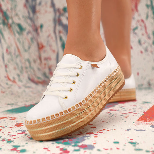 A white sneaker with a platform sole and gold accents.