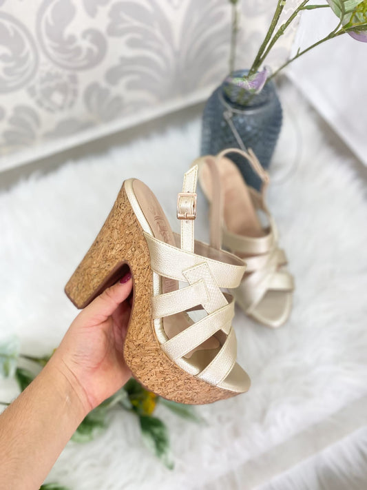 A gold strappy sandal with a cork heel.